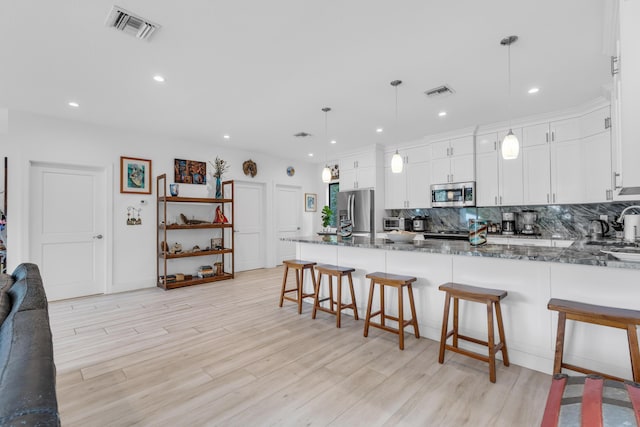 kitchen featuring appliances with stainless steel finishes, pendant lighting, and white cabinets