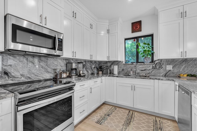 kitchen featuring white cabinetry, appliances with stainless steel finishes, sink, and light stone counters