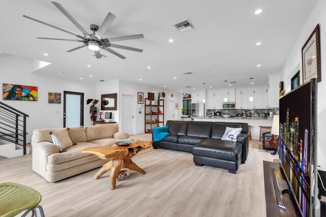 living room with light hardwood / wood-style flooring and ceiling fan