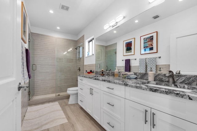 bathroom with vanity, toilet, a shower with shower door, and hardwood / wood-style floors