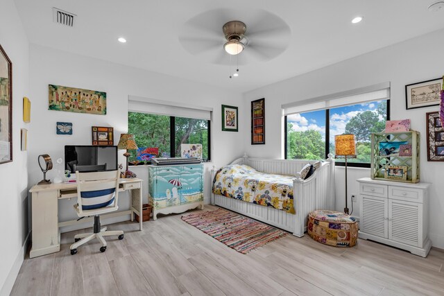 bedroom featuring ceiling fan, multiple windows, and light wood-type flooring