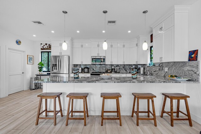 kitchen with pendant lighting, white cabinets, and appliances with stainless steel finishes