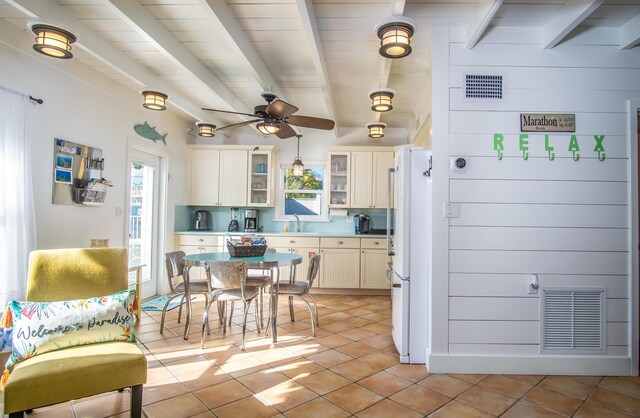 tiled bedroom with beamed ceiling, ceiling fan, and two closets