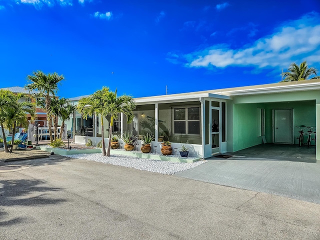 rear view of property featuring a carport and a sunroom