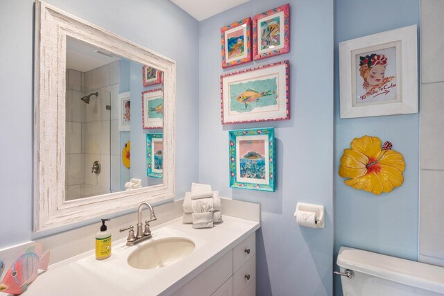 bathroom featuring vanity, toilet, and tiled shower