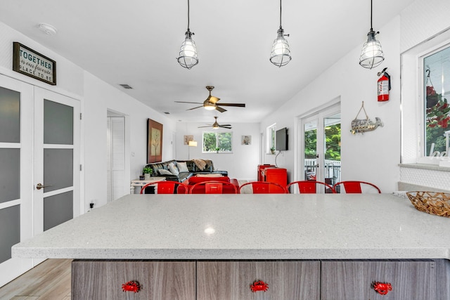 15 Garden Cove Dr, Key Largo, FL 33037 - kitchen with french doors, a ceiling fan, light wood-style floors, light stone countertops, and pendant lighting