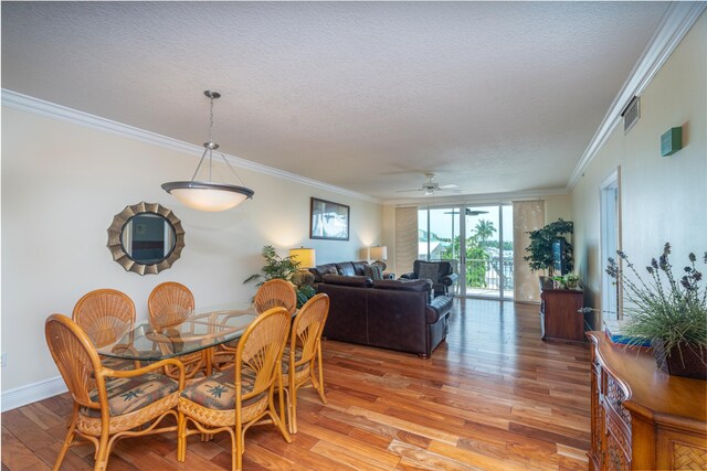 dining space featuring ceiling fan, hardwood / wood-style flooring, ornamental molding, and a textured ceiling