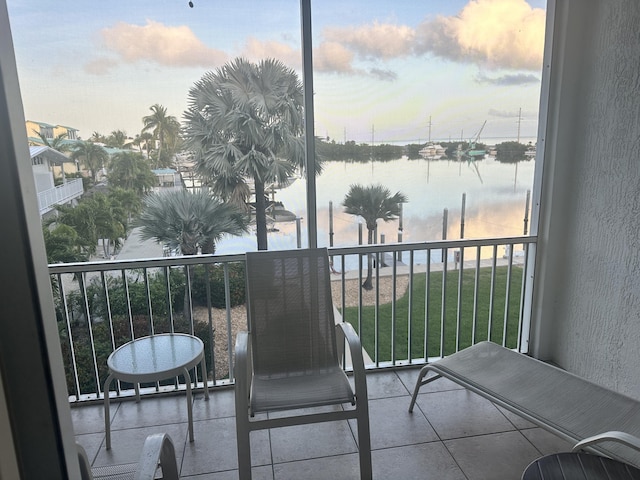 balcony at dusk featuring a water view