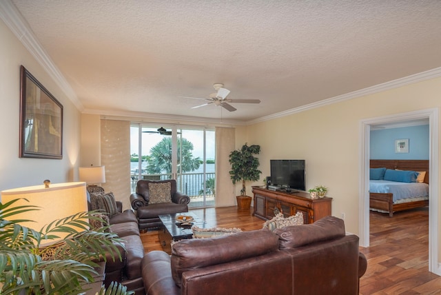 living room featuring ceiling fan, ornamental molding, wood-type flooring, and a textured ceiling