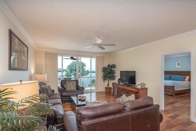 living room with ceiling fan, wood-type flooring, ornamental molding, and a textured ceiling