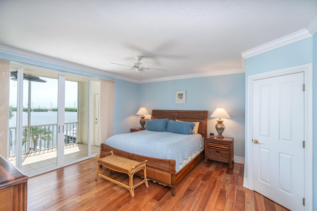 bedroom with a water view, crown molding, wood-type flooring, ceiling fan, and access to exterior