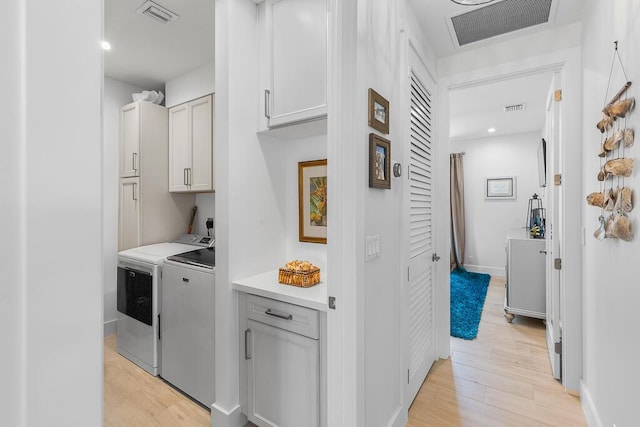 laundry area featuring cabinet space, visible vents, washing machine and dryer, and light wood-style flooring