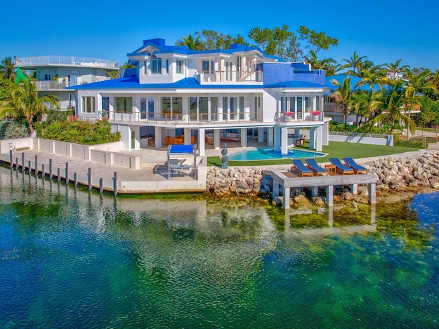 rear view of house with a swimming pool, a patio, a balcony, and a water view