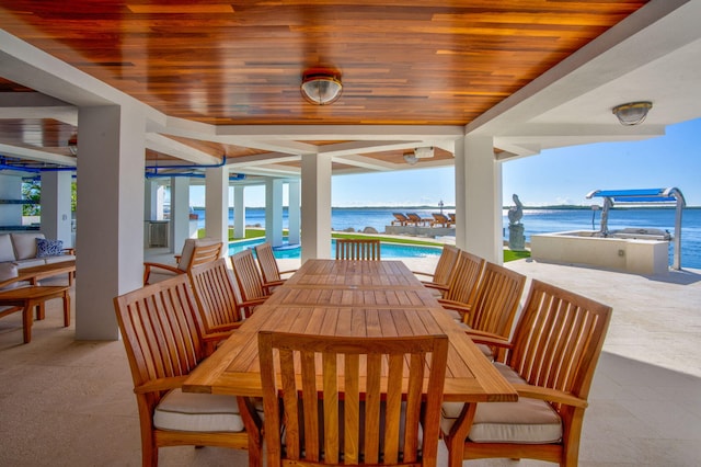 dining area with a water view, a wealth of natural light, and wood ceiling