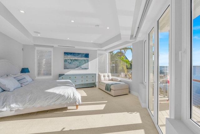 bedroom with access to outside, light colored carpet, and a tray ceiling