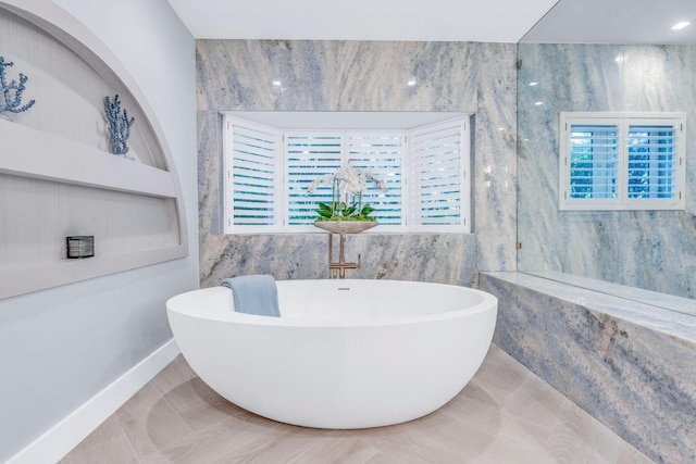 bathroom with a bathing tub, tile patterned flooring, and tile walls