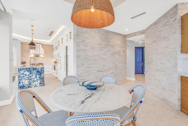 dining area featuring sink, tile walls, and a tray ceiling