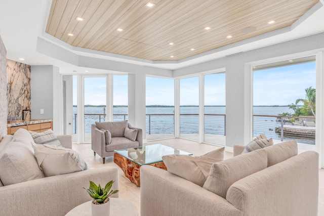 living room with a raised ceiling, a water view, and wood ceiling