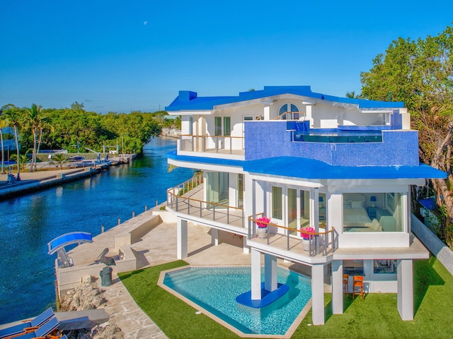 rear view of property featuring a balcony, a water view, and a patio area