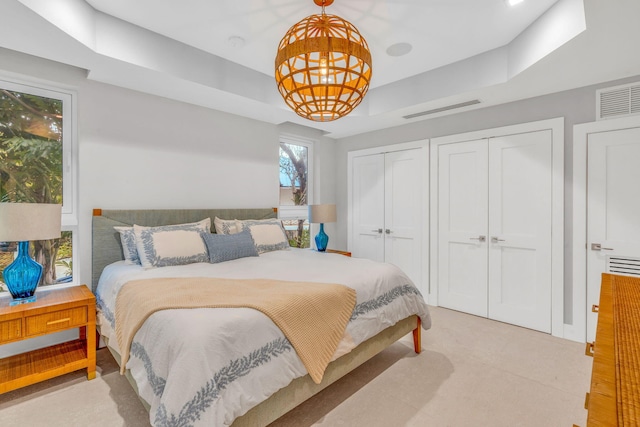 bedroom featuring multiple closets and a raised ceiling