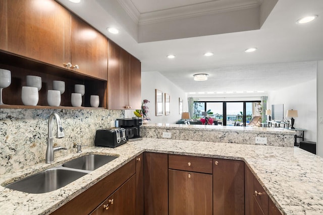 kitchen with light stone counters, kitchen peninsula, sink, and backsplash