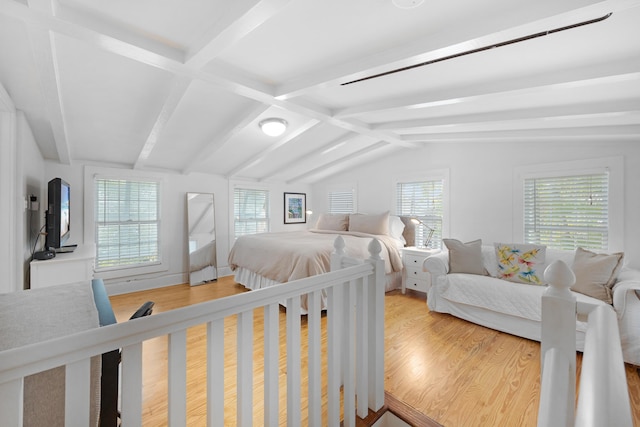 bedroom featuring lofted ceiling with beams, multiple windows, and wood finished floors