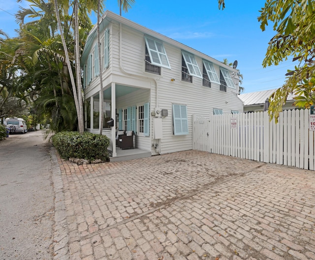 view of front of home with covered porch, a gate, and fence