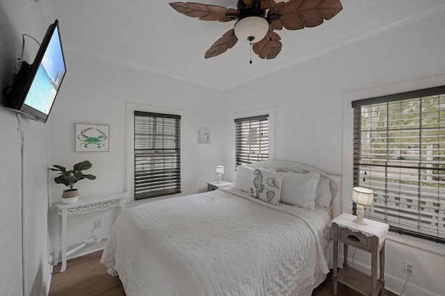 bedroom featuring ornamental molding, a ceiling fan, baseboards, and wood finished floors