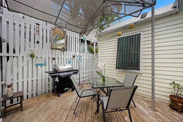 wooden terrace with fence, outdoor dining area, and area for grilling