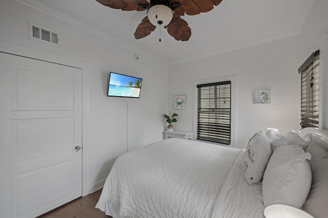 bedroom with a ceiling fan, visible vents, crown molding, and wood finished floors