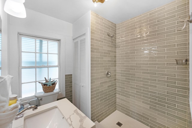 bathroom with a sink, a tile shower, and a closet