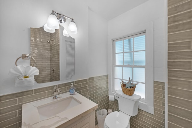 bathroom featuring walk in shower, tile walls, toilet, and vanity