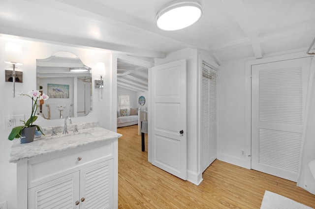 bathroom with baseboards, lofted ceiling with beams, wood finished floors, ensuite bathroom, and vanity