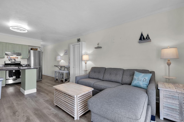 living area featuring baseboards, crown molding, and wood finished floors