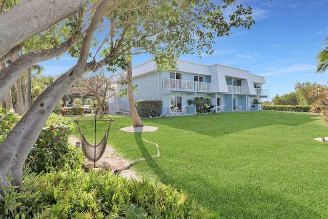 exterior space featuring a balcony, stucco siding, and a yard