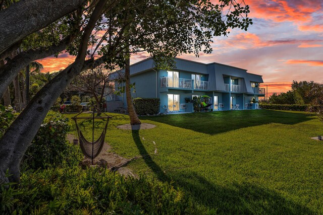 back of property with a balcony, stucco siding, and a yard