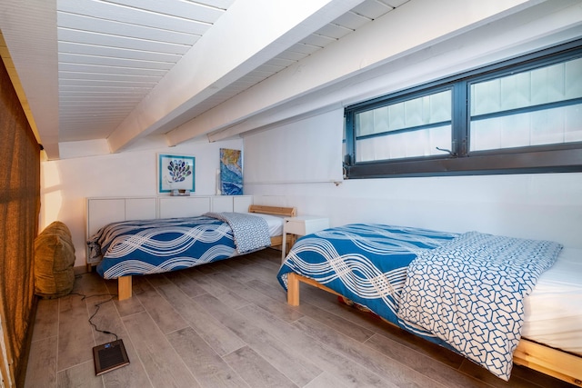 bedroom featuring hardwood / wood-style flooring and beamed ceiling