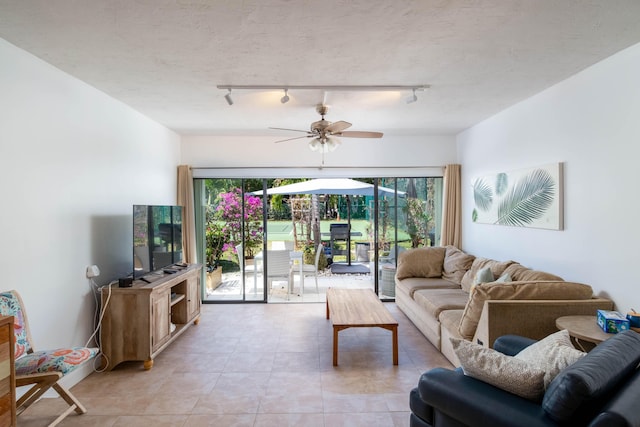 living room featuring ceiling fan, light tile patterned floors, and a textured ceiling