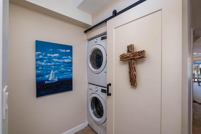 washroom featuring stacked washer / drying machine and a barn door