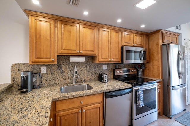 kitchen featuring light tile patterned flooring, appliances with stainless steel finishes, sink, decorative backsplash, and light stone counters