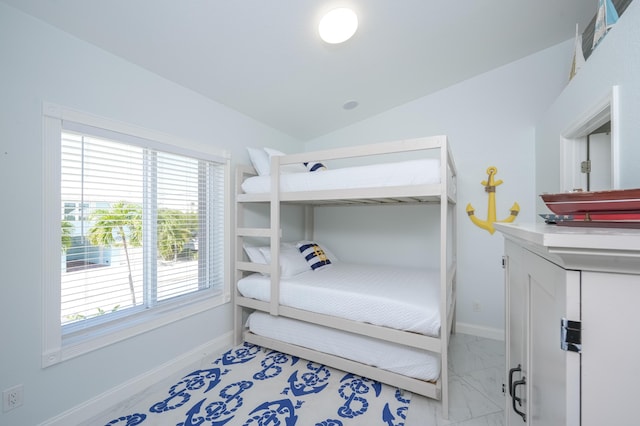 bedroom with lofted ceiling, multiple windows, marble finish floor, and baseboards
