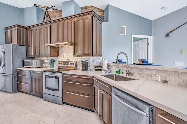 kitchen featuring a sink, tasteful backsplash, marble finish floor, light stone counters, and appliances with stainless steel finishes