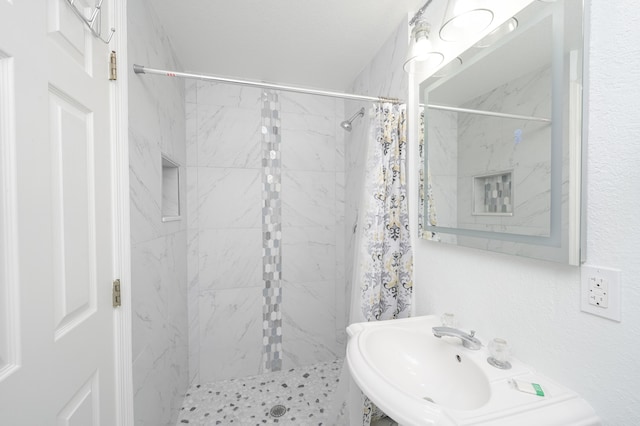full bathroom with a tile shower and a sink