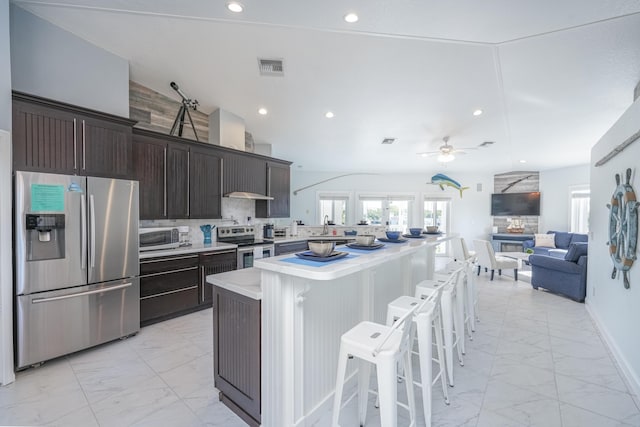 kitchen featuring a breakfast bar, appliances with stainless steel finishes, light countertops, marble finish floor, and ceiling fan