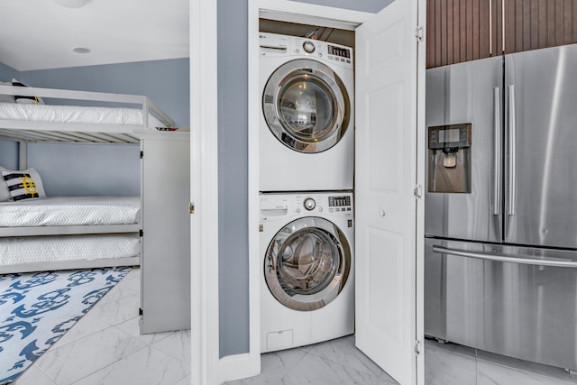 laundry room featuring stacked washer and clothes dryer, laundry area, and marble finish floor
