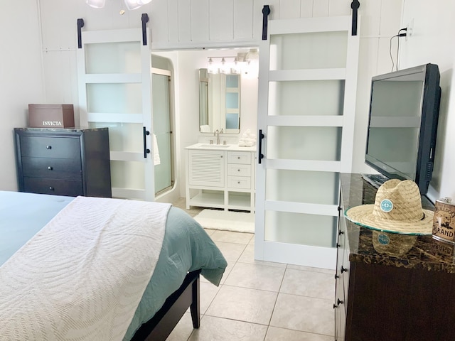 tiled bedroom featuring a barn door, sink, and connected bathroom