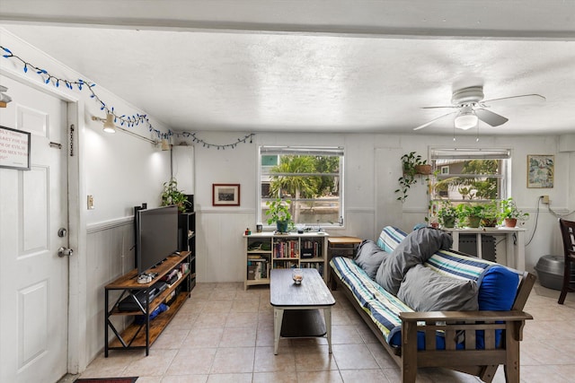 tiled living room featuring ceiling fan and a textured ceiling