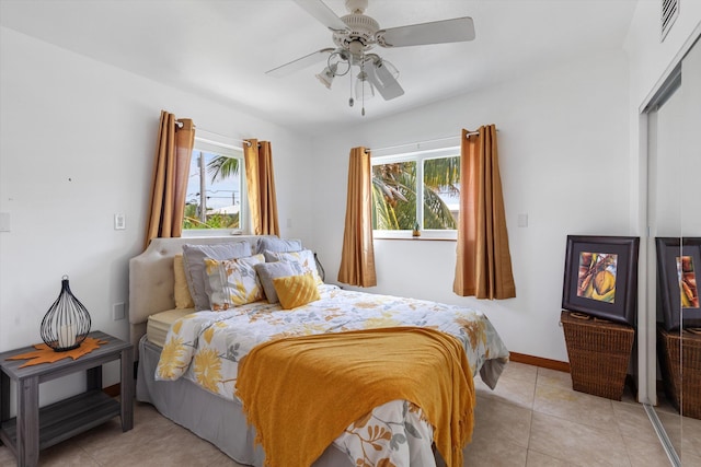 bedroom featuring multiple windows, light tile patterned floors, a closet, and ceiling fan