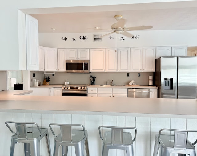 kitchen featuring white cabinetry, appliances with stainless steel finishes, a breakfast bar, and sink