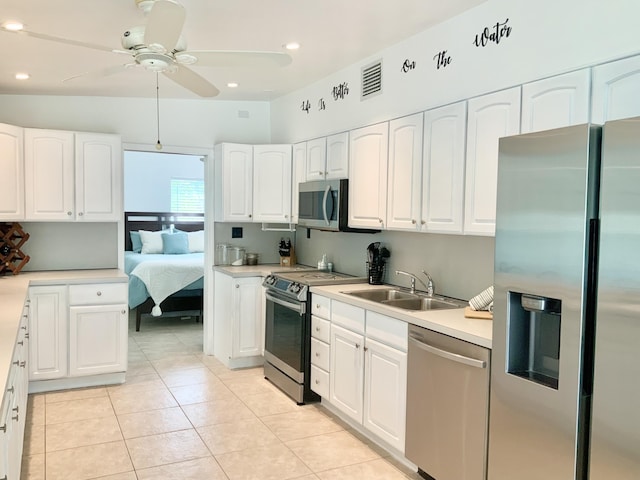 kitchen with sink, light tile patterned floors, ceiling fan, stainless steel appliances, and white cabinets